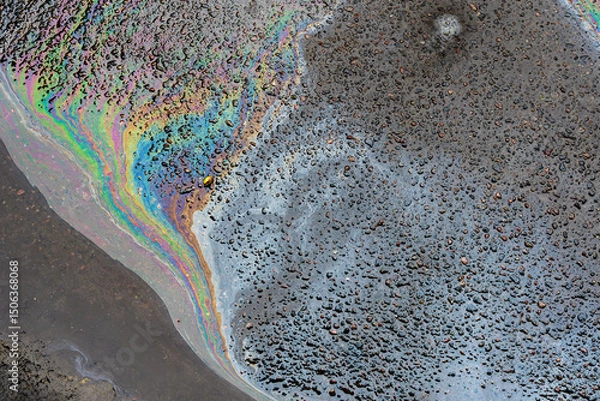 Fototapeta Colorful gasoline or oil spill creating rainbow sheen reflecting on wet asphalt road after rain, environmental pollution concept.