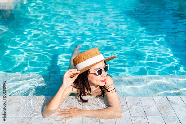 Fototapeta Young happy woman traveler relaxing and enjoying a tropical resort pool while traveling for summer vacation, Travel concept