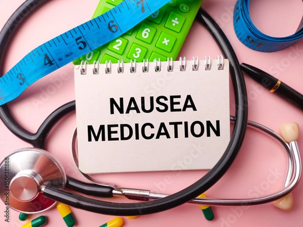 Fototapeta Notebook and doctor's equipment with the word NAUSEA MEDICATION on a pink background