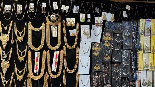 Fototapeta Ornate Indian jewelry of gold and multiple colors is elegantly displayed against a dark background