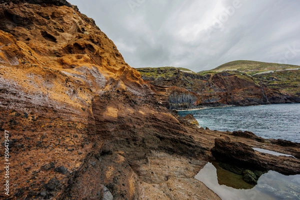 Fototapeta Dramatic geological formations along a rugged coastline with ocean views, showing volcanic layers, erosion textures and natural detail.