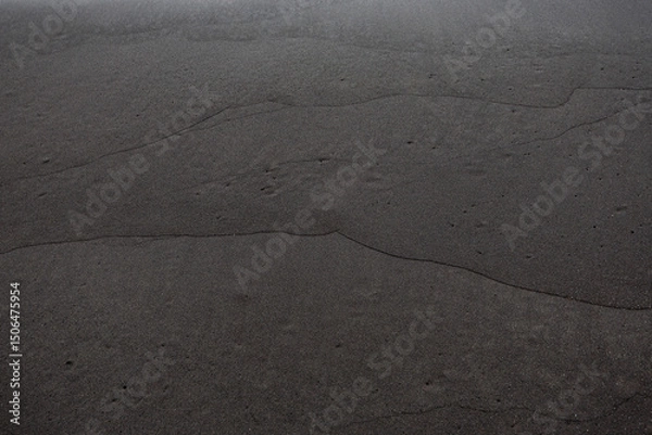 Fototapeta Smooth black volcanic sand with subtle wave-shaped lines, creating a minimal abstract texture useful for backgrounds or design purposes.