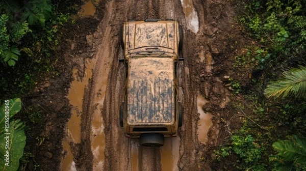 Fototapeta Top-down view of an overlanding vehicle resting on rugged terrain, coated in dried and wet mud, with deep tire tracks leading into dense forest—capturing the raw aftermath of extreme off-road travel
