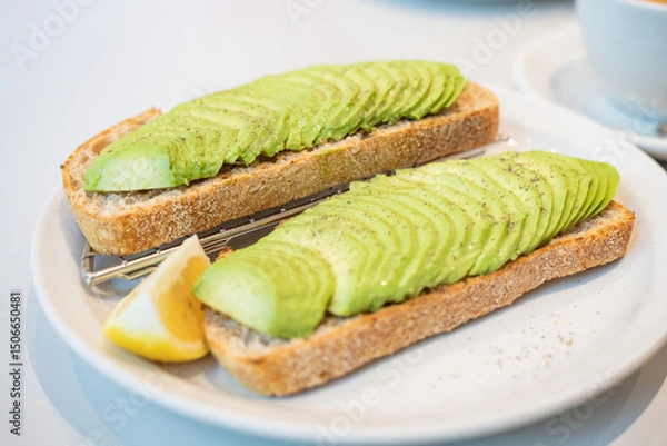 Fototapeta Top down view of two toast bread with sliced avocado topping. Tsuen Wan, Hong Kong. Selective focus, blurred background.