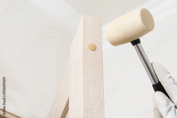 Fototapeta Installation of door plugs by a master using a rubber hammer, close-up