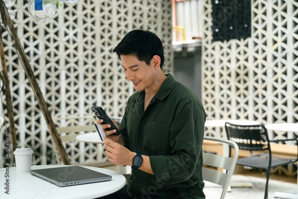 Fototapeta Adult asian man using mobile phone and credit card to complete a transaction