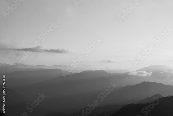 Obraz Landscape of the mountain range with sunlight beams through the haze at sunset