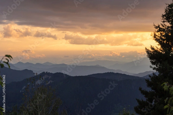 Obraz Landscape photo of the mountain range with partly cloudy sky at sunset.