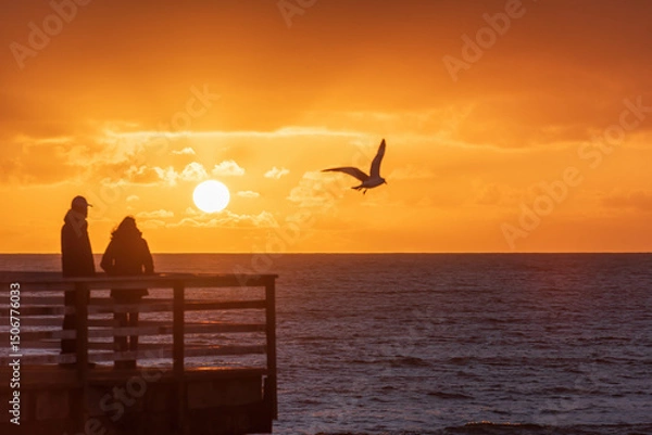 Obraz A couple watching a sunset over the ocean