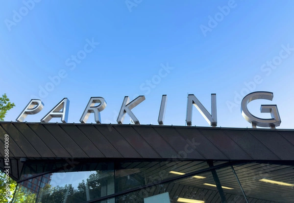 Obraz PARKING sign on the roof. Metallic letters text on blue sky background