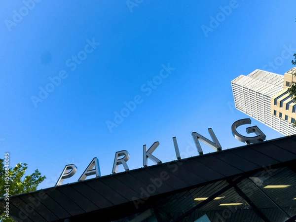 Obraz PARKING sign on the roof. Metallic letters text on blue sky background