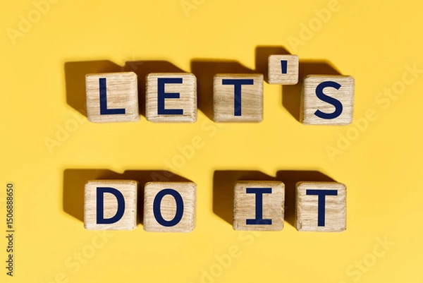 Fototapeta Let's do it motivation phrase on wooden blocks over yellow background