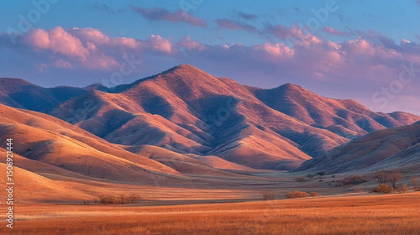 Fototapeta Sunset over desert mountains with soft pink and blue sky, serene evening landscape with textured hills for travel or natural design