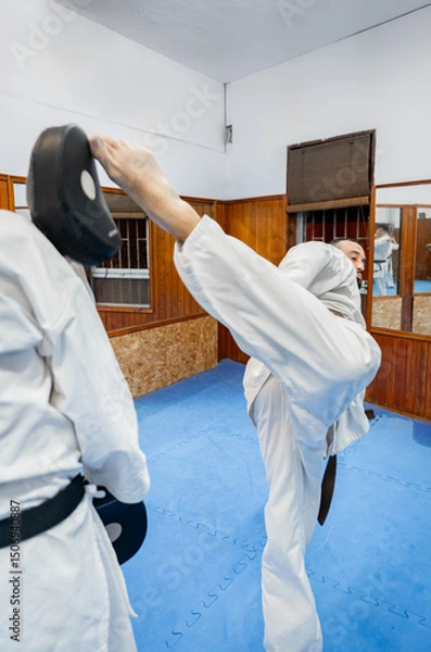 Fototapeta Karate athletes training kicking and blocking techniques in dojo