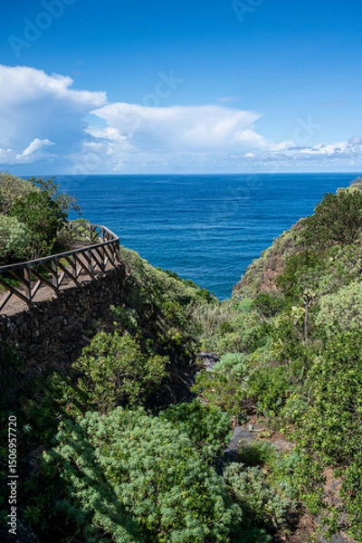 Fototapeta A beautiful view of the ocean with a bridge in the background. The bridge is wooden and has a railing. The ocean is calm and the sky is clear