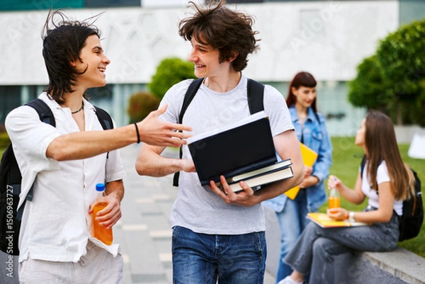Obraz Two cheerful male students talking and walking on university campus