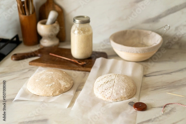 Obraz Freshly prepared sourdough bread dough rests on parchment near a container of active starter and a mixing bowl, showcasing the art of home baking.
