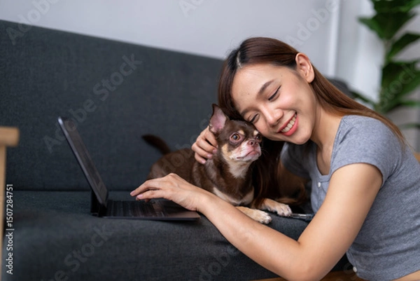 Obraz A woman is sitting on a couch with a small dog