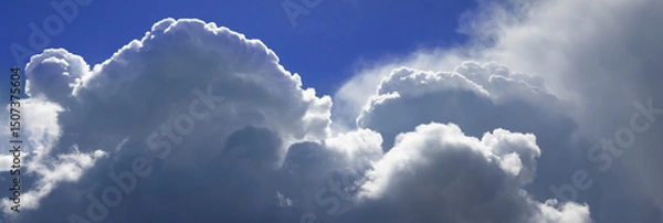 Fototapeta Majestic cumulus clouds drifting across a vibrant blue sky, hinting at an approaching storm during the afternoon