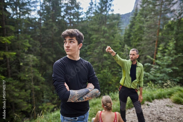 Fototapeta Young man and guide exploring a forest trail in the mountains during sunny summer day