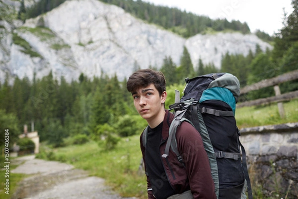 Fototapeta Young hiker pauses to take in the breathtaking mountain view during an outdoor adventure