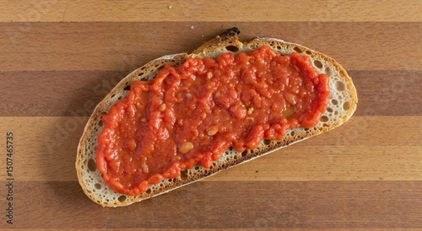 Fototapeta Slice of bread topped with red tomato sauce on wooden board  