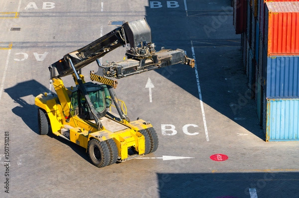 Obraz Yellow Reach Stacker Moving Between Shipping Containers in Cargo Terminal