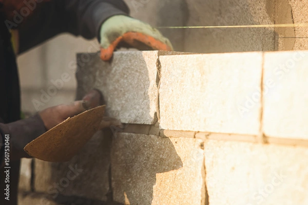 Obraz Close-up of skilled bricklayer working on construction site laying bricks for wall construction