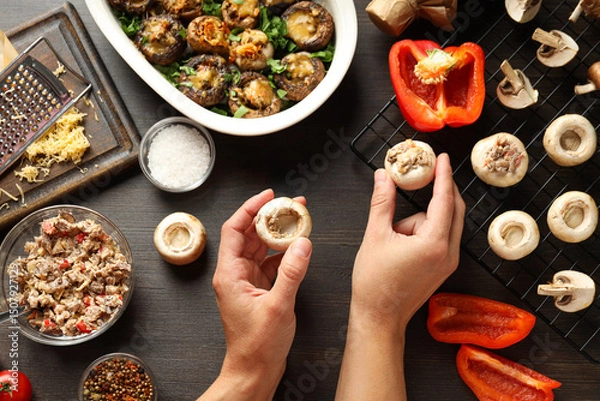 Obraz Stuffed mushrooms, kitchen board, ingredients and hands on wooden background, top view