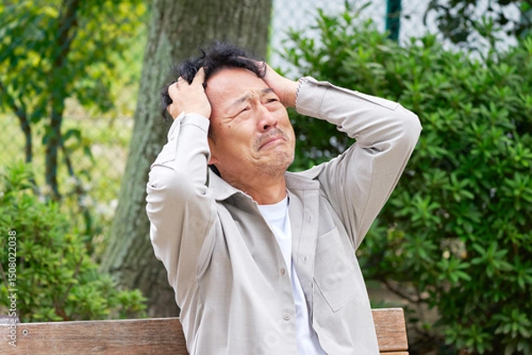 Obraz 中年の男性　頭を抱える　公園