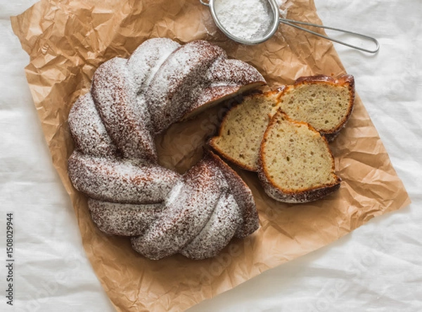 Fototapeta Slices of a traditional banana cake with powdered sugar on a light background, top view