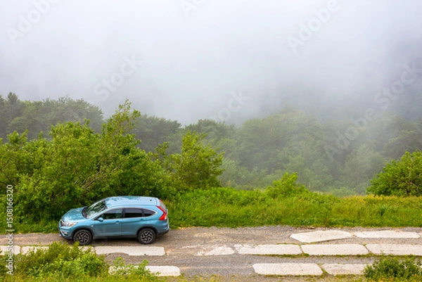 Fototapeta perechyn, ukraine - 22 ju2 2019: 4wd car on a countryside mountain road. reliable 4wd suv for a journey on the edge of a hill. explore highland of ukraine on a misty forenoon in summer