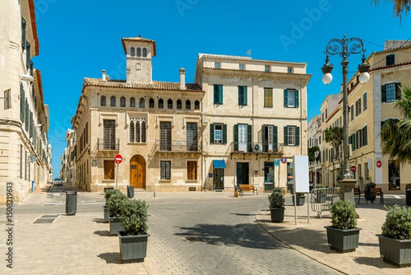 Fototapeta Historic architecture under a blue sky on a small town square in Mahon, Spain.