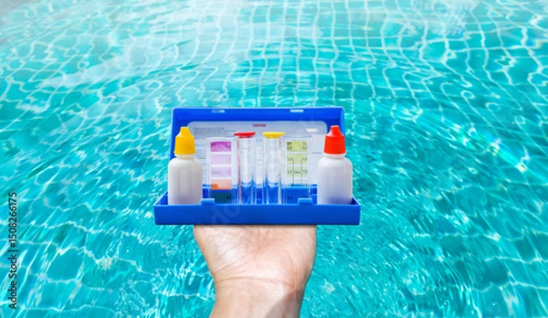 Fototapeta Water tester test kit in girl hand over blurred clear swimming pool water background, quality water test tool for swimming pool
