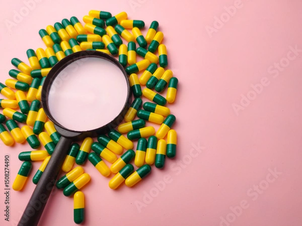 Fototapeta Medicine pill and magnifying glass on a pink background with copy space