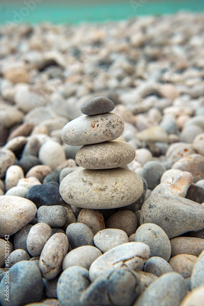 Fototapeta beautiful grey and white pebbles stacked on a beach and turquoise sea in background