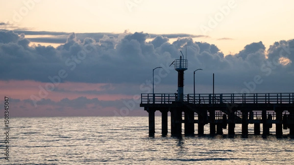 Obraz Silhouette of a Pier with Lighthouse at Sunset — Dramatic Sky over Calm Sea