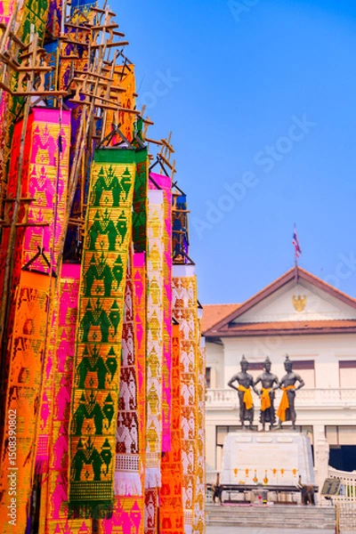 Fototapeta A vibrant display of traditional Lanna flags (Tung) in various colors, rising against a clear blue sky, part of a cultural festival in Northern Thailand.