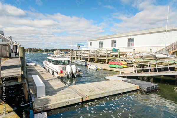 Fototapeta Boats moored to jetties and dinghies on a wooden pier in a harbour on a sunny autumn day