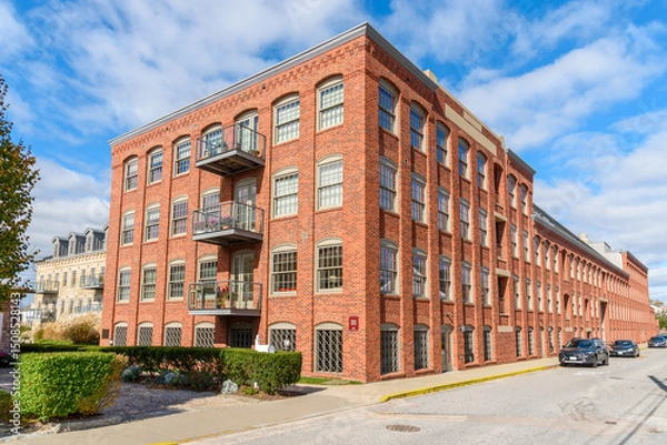 Fototapeta Historic brick warehouse renovatd and converted into apartment lofts under blue sky on a sunny autumn day
