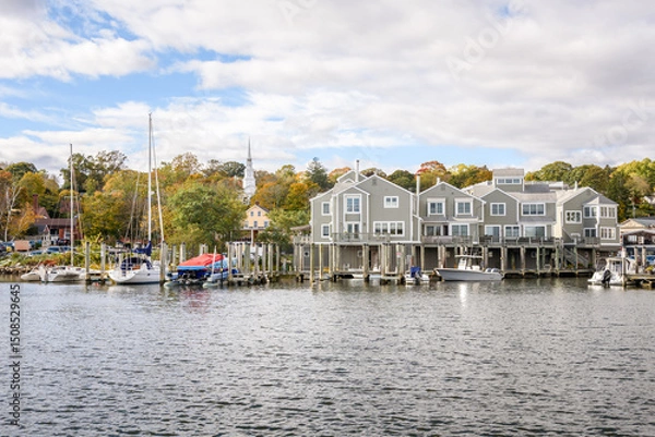 Fototapeta Waterfront apartments with private wooden jetties on a river on a partly cloudy autumn day