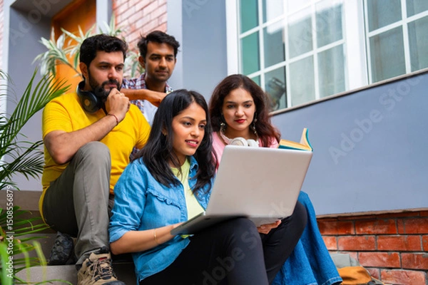 Obraz Indian classmates using laptop and books while studying together in friendly outdoor campus setting