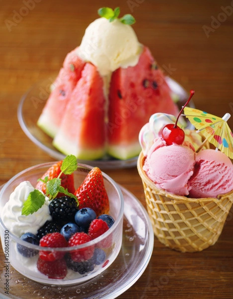Fototapeta Summertime treats featuring ice-cream garnished with fresh fruits selection of watermelon, strawberries, blackberries and cherry arranged on the table. Summer delicious dessert