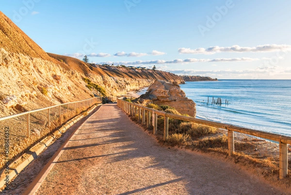 Fototapeta Walking trail to Port Willunga beach, while old jetty ruins can be seen in the sea at sunset time, Fleurieu Peninsula, South Australia
