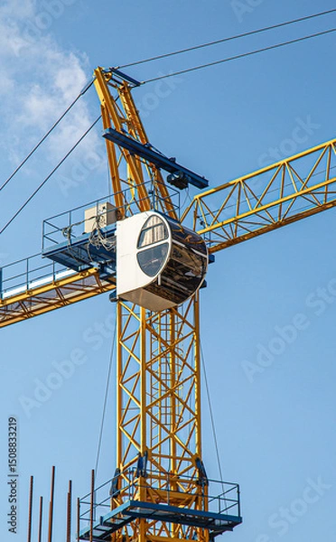 Fototapeta Tall building under construction with scaffolds,Freestanding tower crane on a building site.Building construction site work against blue sky