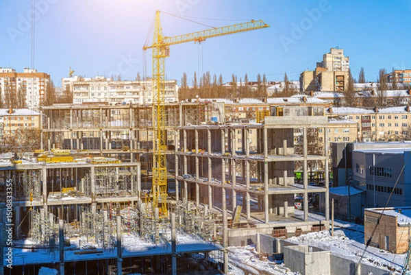 Fototapeta Tall building under construction with scaffolds,Freestanding tower crane on a building site.Building construction site work against blue sky
