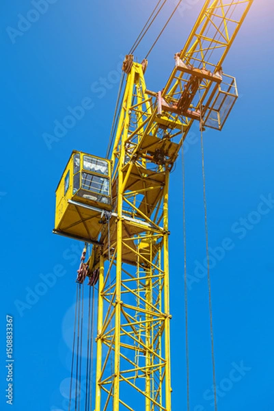 Fototapeta Tall building under construction with scaffolds,Freestanding tower crane on a building site.Building construction site work against blue sky