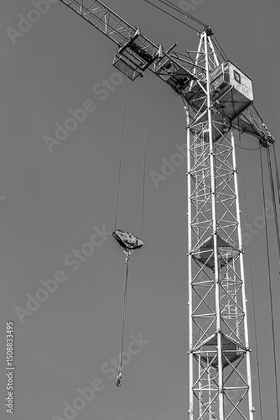 Fototapeta Tall building under construction with scaffolds,Freestanding tower crane on a building site.Building construction site work against blue sky