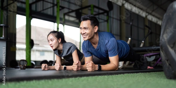 Fototapeta Wellness and Friendship. Friends engaged in a plank exercise at the gym.
