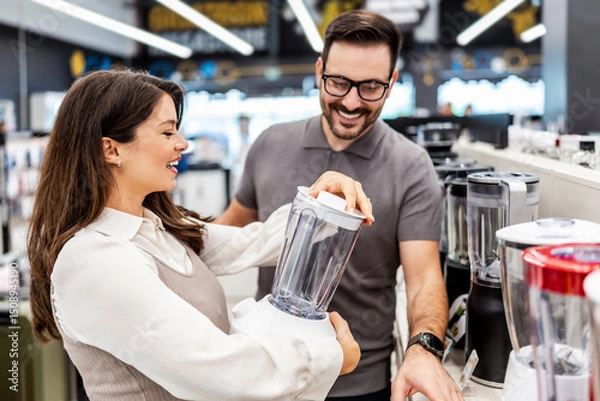 Obraz Smiling shop assistant helping a pregnant customer choose home appliances while showcasing various products in a vibrant electronics store